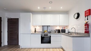 A modern kitchen with white cabinets, a microwave, a coffee maker, and a fire extinguisher. - Pristine Flat Ideal for Small Groups Sleeps 4 (Manchester)