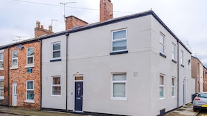 A two-story residential building with a white facade, a dark blue door, and a visible chimney. - Stunning City Centre Home Perfect For Couples (Chester)