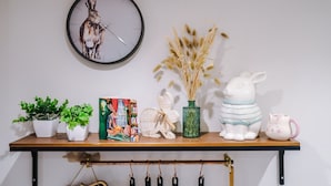A shelf with a clock, potted plants, a decorative vase, and figurines. - Stunning City Centre Home Perfect For Couples (Chester)