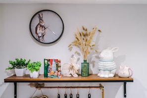 A shelf with a clock, potted plants, a decorative vase, and figurines. - Stunning City Centre Home Perfect For Couples (Chester)