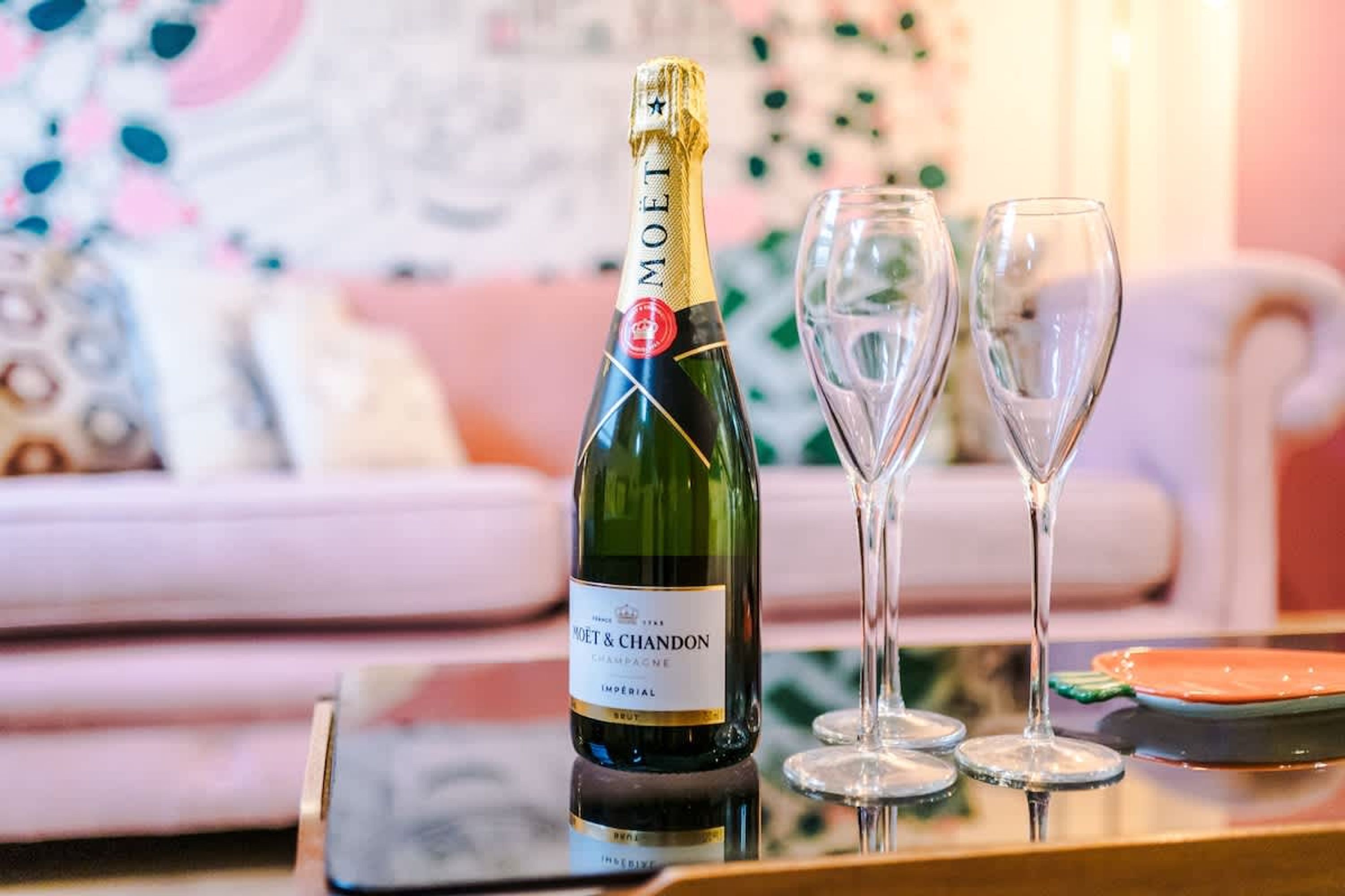 A bottle of Moët & Chandon champagne and two empty glasses on a table.
