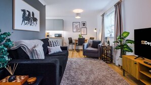 Un soggiorno moderno con un divano, una TV e un'area pranzo con tavolo e sedie.