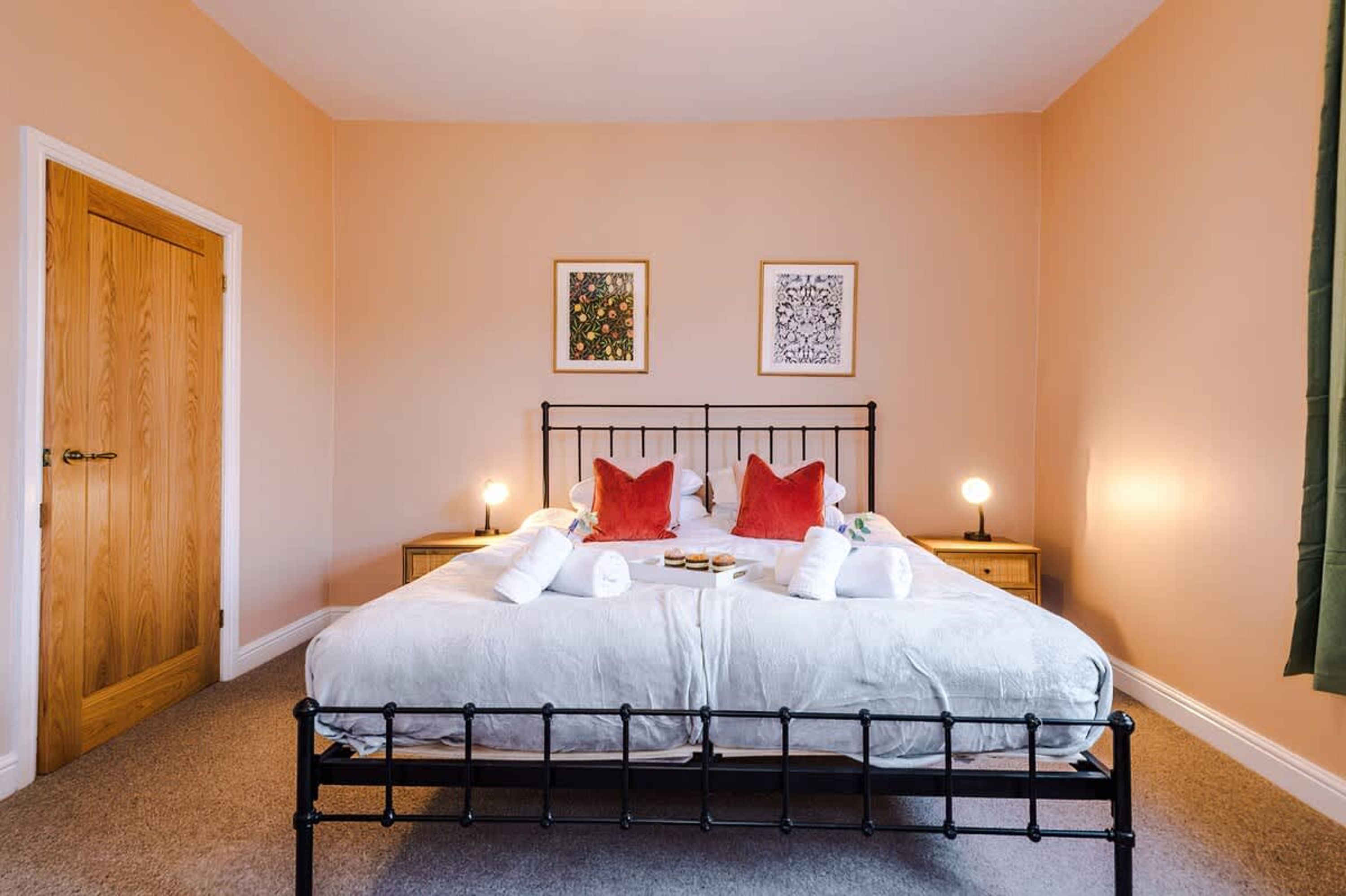 Un lit double avec un cadre en métal, deux tables de chevet avec des lampes et deux tableaux encadrés accrochés au mur.