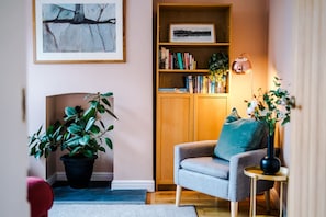 Una sala de estar acogedora con una estantería, una planta en maceta, un sofá y una lámpara.