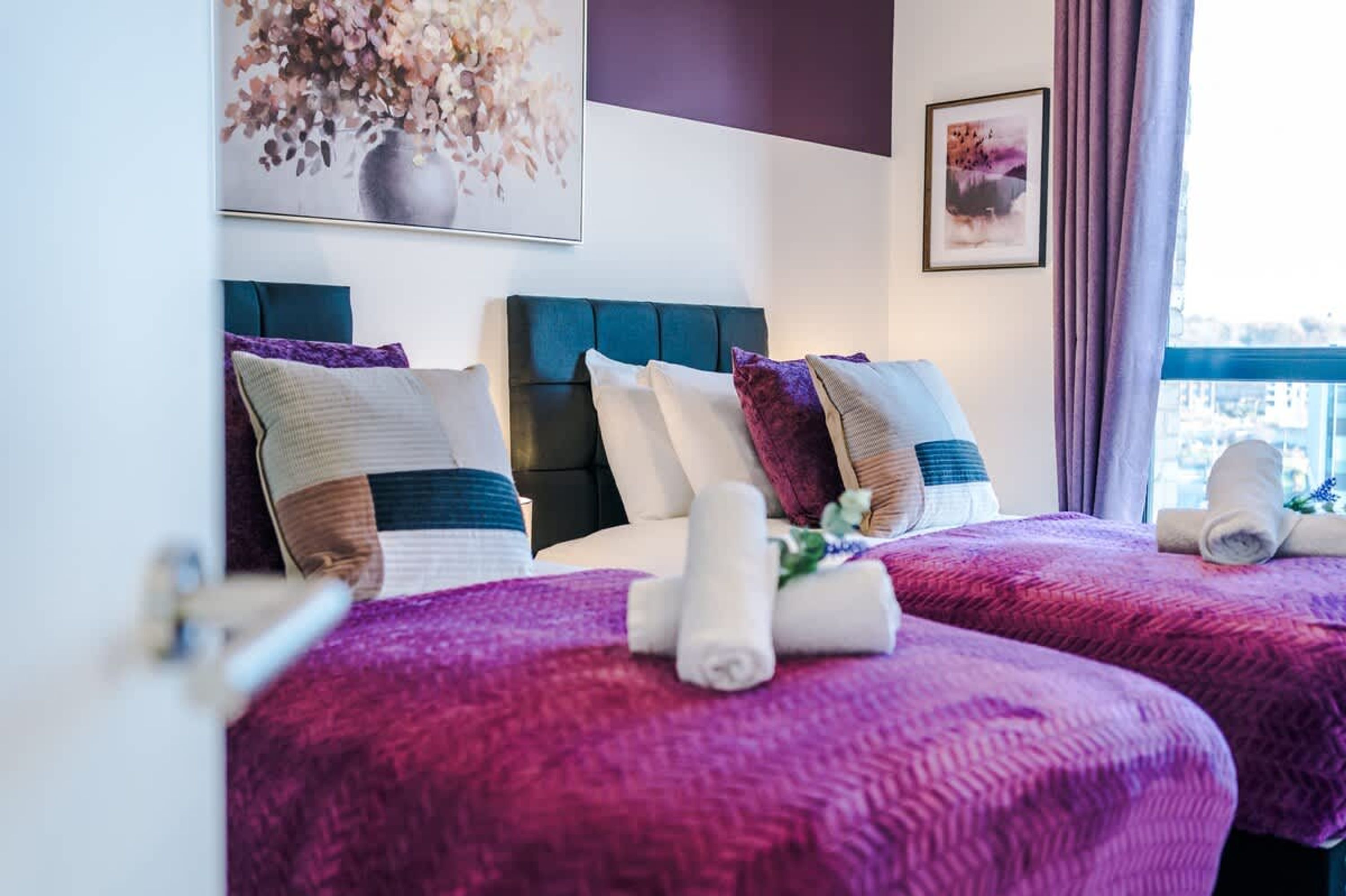 Ein Hotelzimmer mit zwei Betten, einem großen Fenster und Bildern an der Wand.