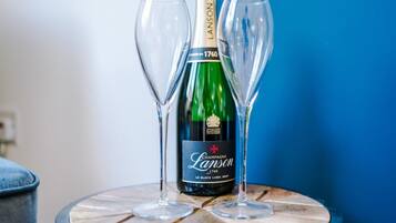 Una ampolla de xampany Lanson 1760 amb dos vasos buits sobre una taula rodona.