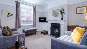 A living room with a fireplace, a television, and a sofa. - NEW Spacious Stylish Home City Centre Sleep 4 (Chester)