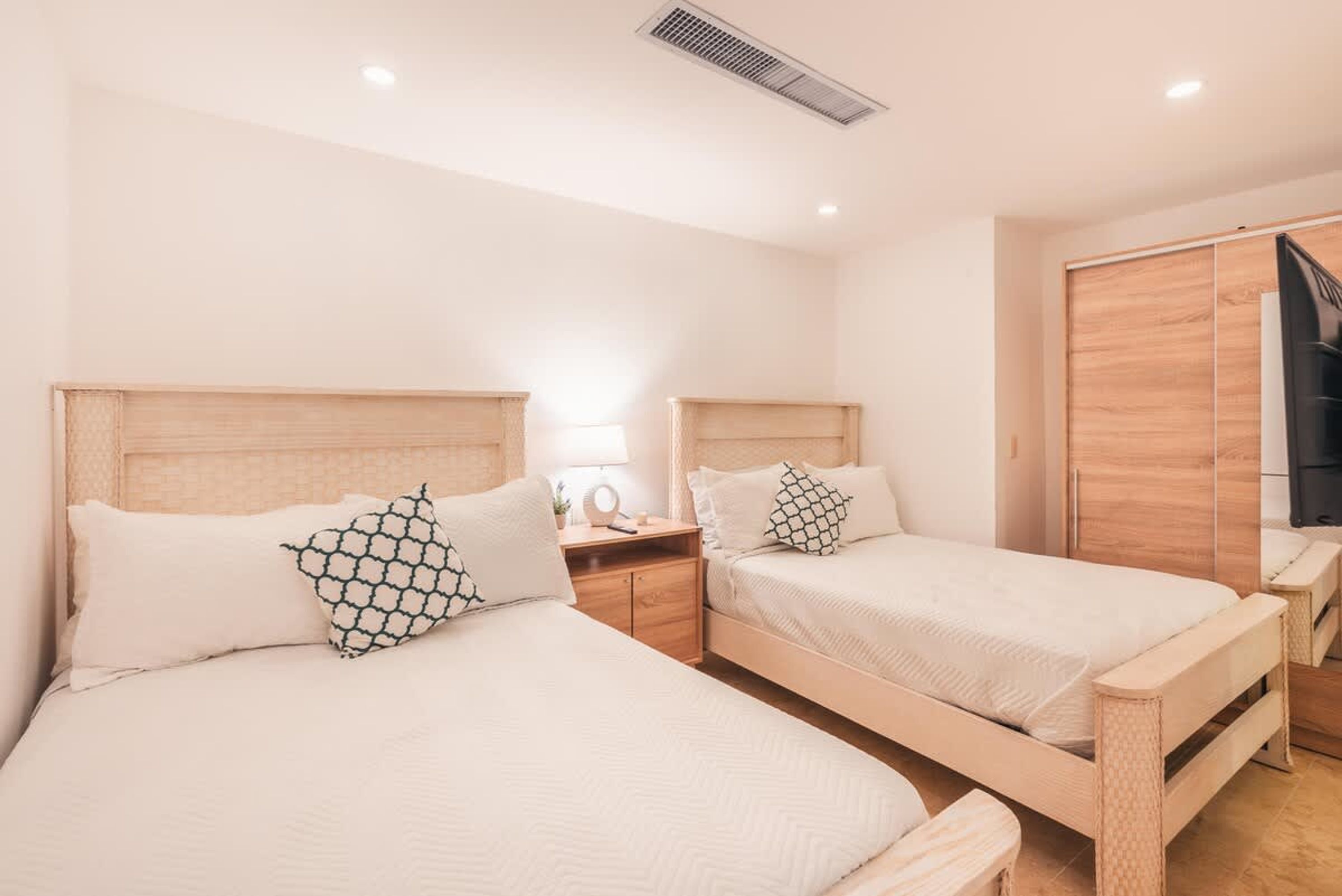 Un dormitorio con dos camas, cabeceros de madera, mesitas de noche y un armario.