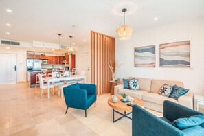 Ein modernes Wohnzimmer mit einer Couch, Sesseln, einem Couchtisch und einem Essbereich mit Tisch und Stühlen.