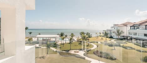 A resort with a pool, palm trees, and a view of the ocean.