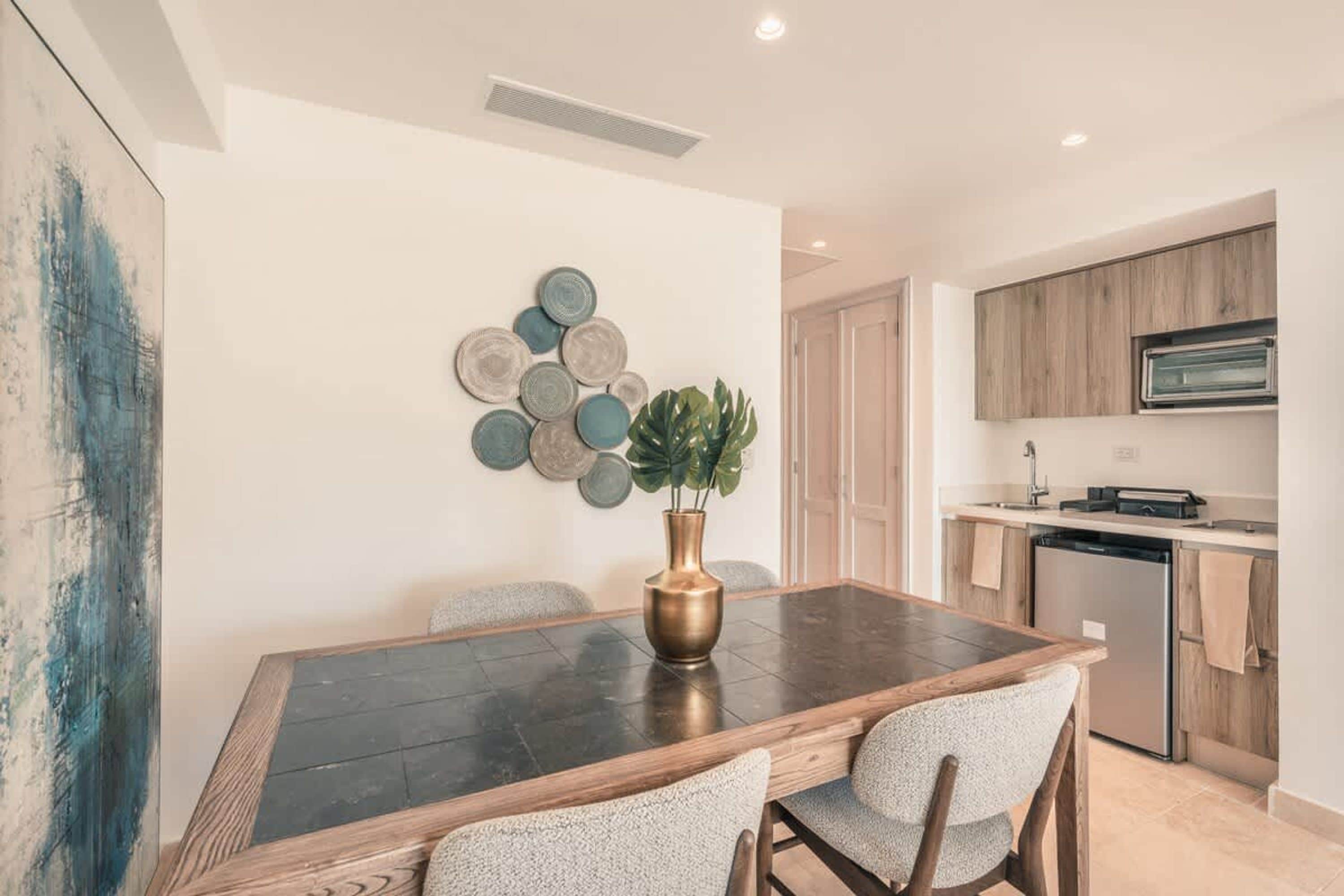 Un comedor con una mesa de madera oscura, cuatro sillas y un jarrón con planta.