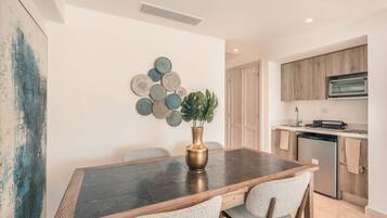 Un comedor con una mesa de madera oscura, cuatro sillas y un jarrón con planta.