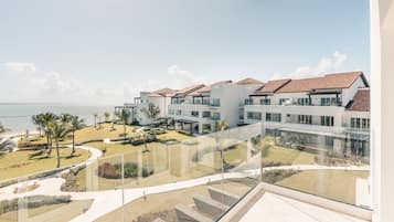 A modern hotel with a pool, outdoor seating, and a view of the ocean.