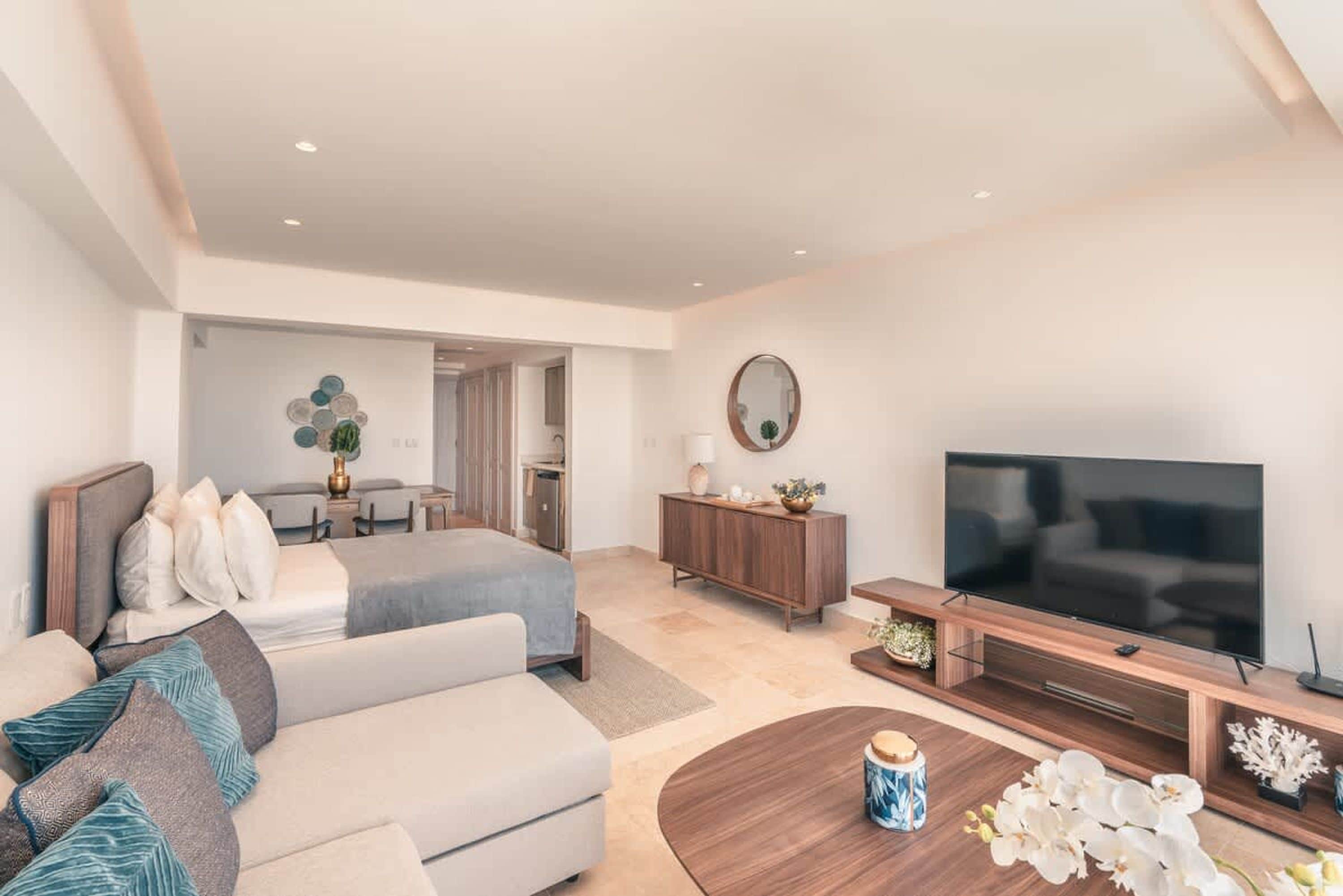 Een moderne hotelkamer met een bed, een bank, een televisie en een zithoek.
