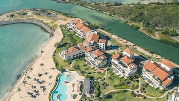 Vista aèria d'un complex turístic amb diversos edificis, una piscina i una platja.