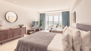 Ein modernes Hotelzimmer mit Bett, Fernseher, Schreibtisch und Meerblick.