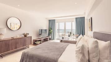 Una habitación de hotel moderna con una cama, un televisor, un escritorio y vistas al mar.