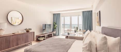 Et moderne hotelværelse med seng, fjernsyn, skrivebord og havudsigt.