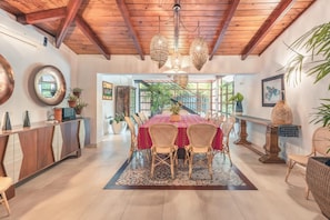 A dining area with a wooden ceiling, round mirrors, wicker chairs, and a central table with a red tablecloth. - 5br Villa Nearby the Beach w Pool in Casa de Campo (La Romana)