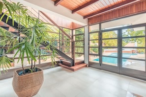 A spacious indoor area with a staircase, large windows, and a pool visible through the glass doors. - 5br Villa Nearby the Beach w Pool in Casa de Campo (La Romana)