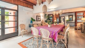 A dining area with a large table, wicker chairs, and hanging wicker lamps. - 5br Villa Nearby the Beach w Pool in Casa de Campo (La Romana)