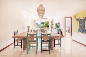 Ein Essbereich mit Holztisch und Stühlen, einer Chandelierleuchtre und Blick durch eine Glastür.