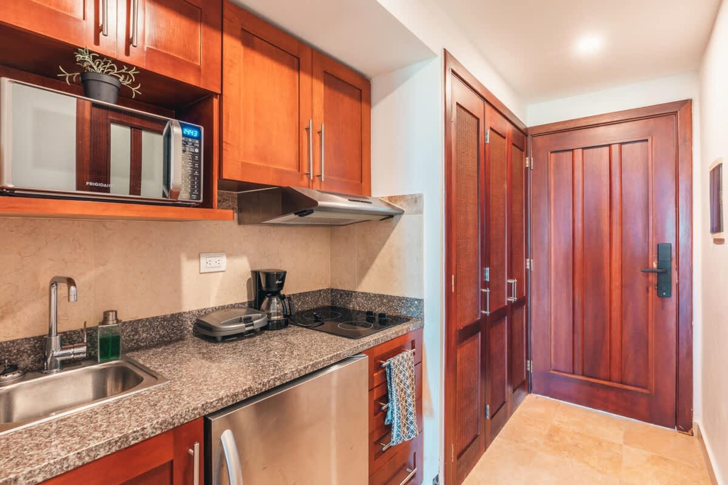 A kitchen with wooden cabinets, a stainless steel sink, a microwave, and a stove.