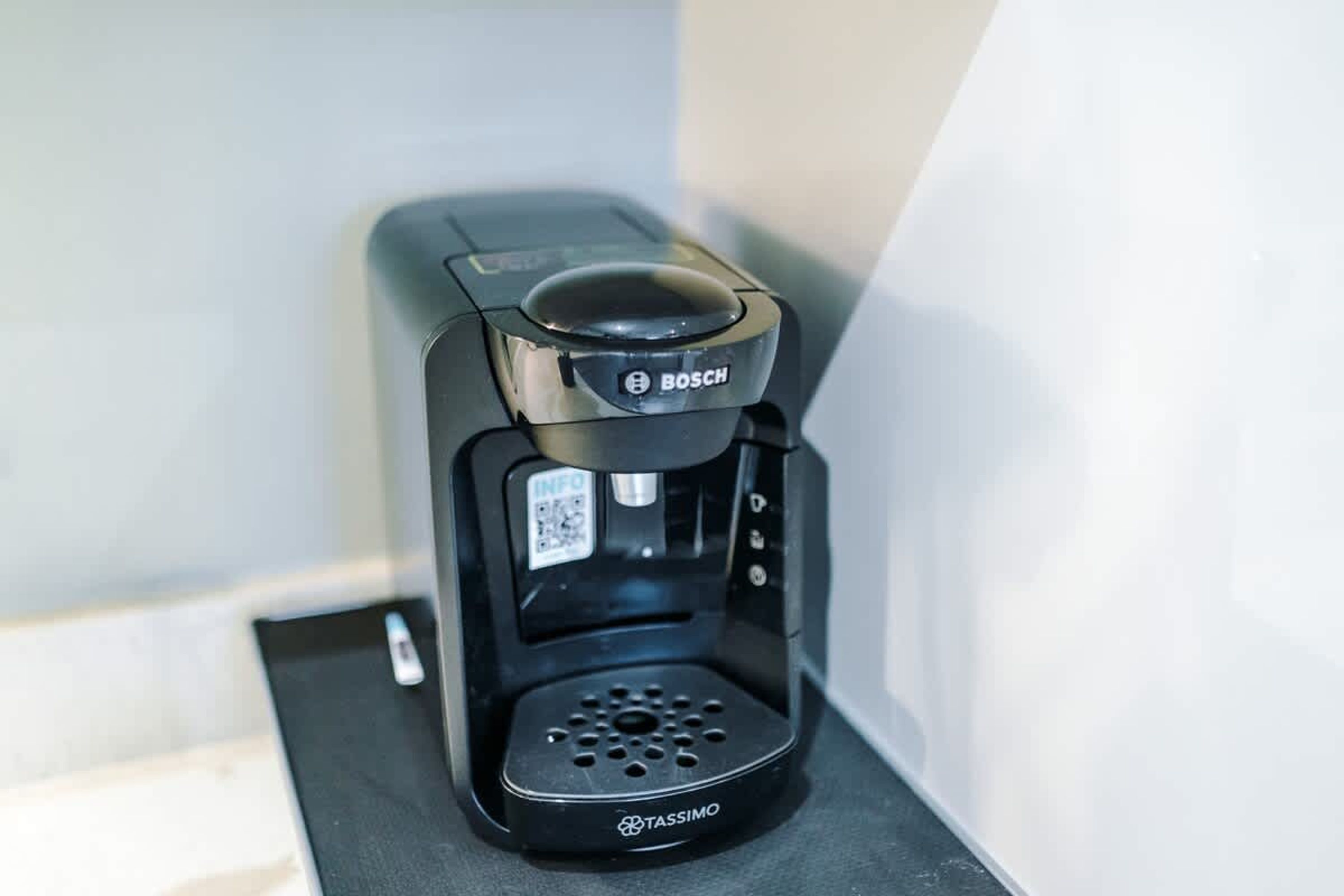 Cafetera negra con un código QR y la marca 'BOSCH', sobre una superficie oscura.