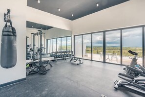 Ein Fitnessraum mit Trainingsgeräten, einem Sandsack und großen Fenstern mit Blick.