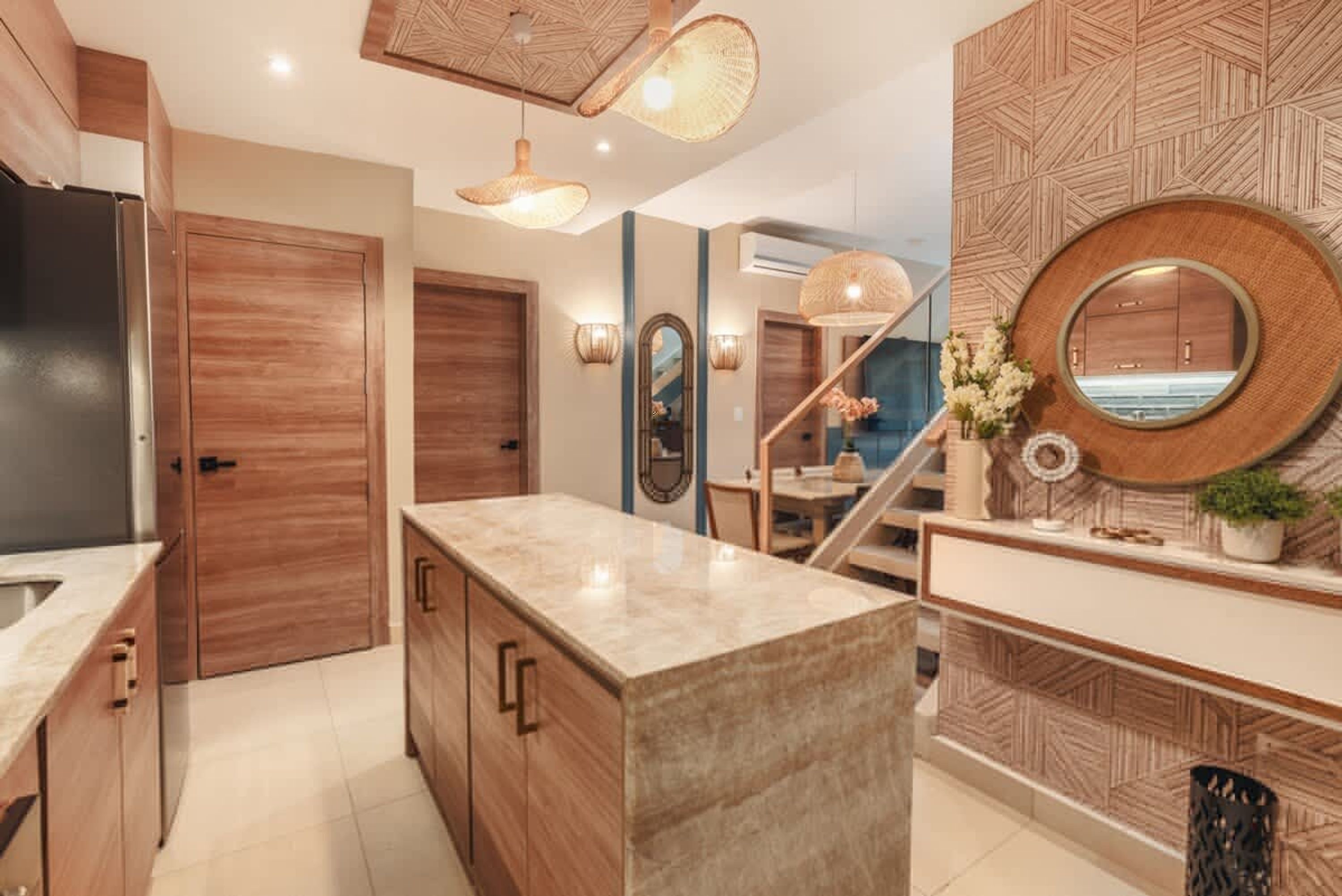 Eine moderne Küche mit Holzschränken, einer Marmorarbeitsplatte und einer Treppe, die in ein Obergeschoss führt.