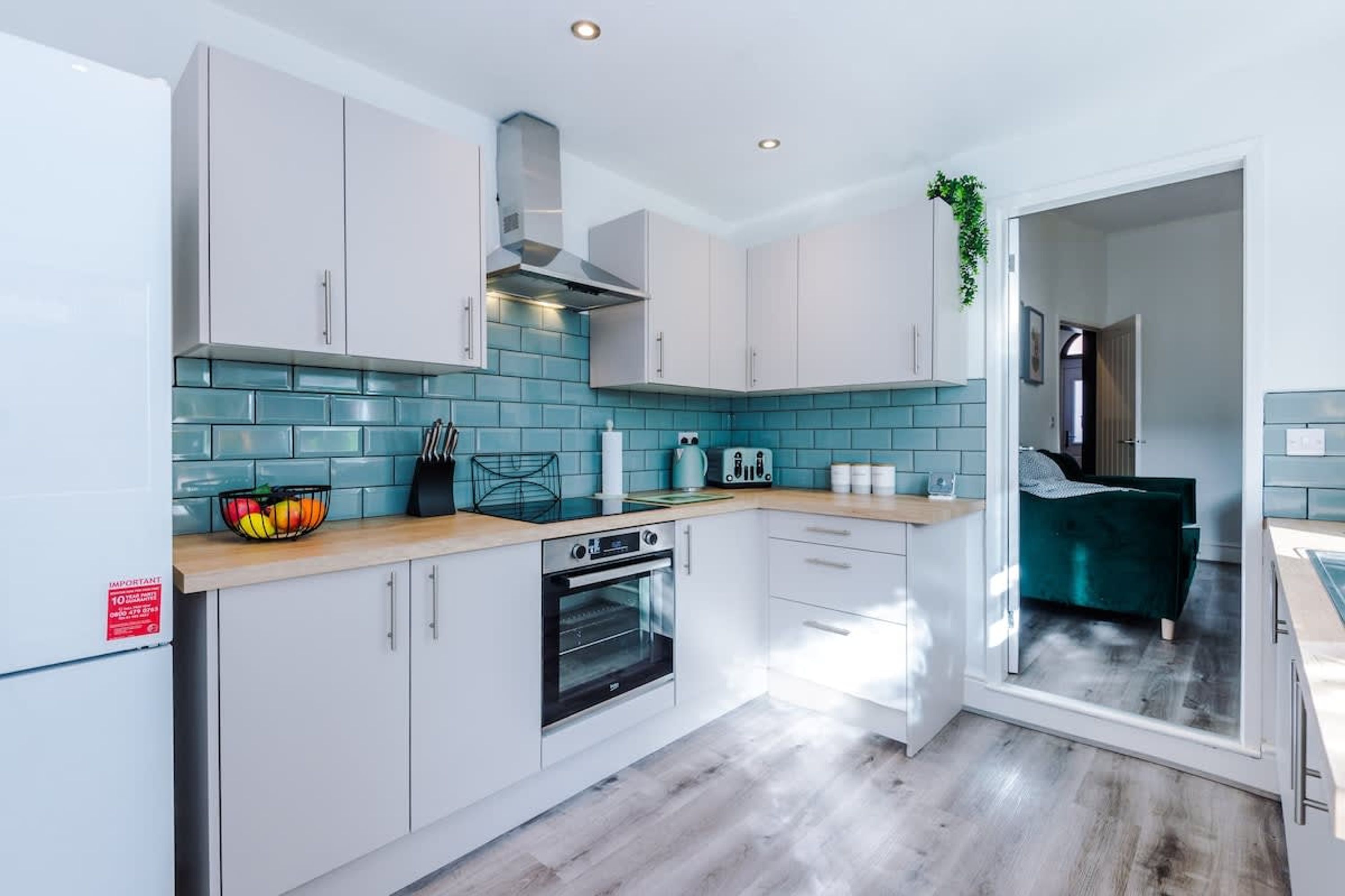 Una cocina moderna con armarios blancos, salpicadero de azulejos azules y horno empotrado.