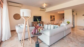 Ein modernes Wohnzimmer mit einer Couch, einer Stehlampe und einem Fernseher.