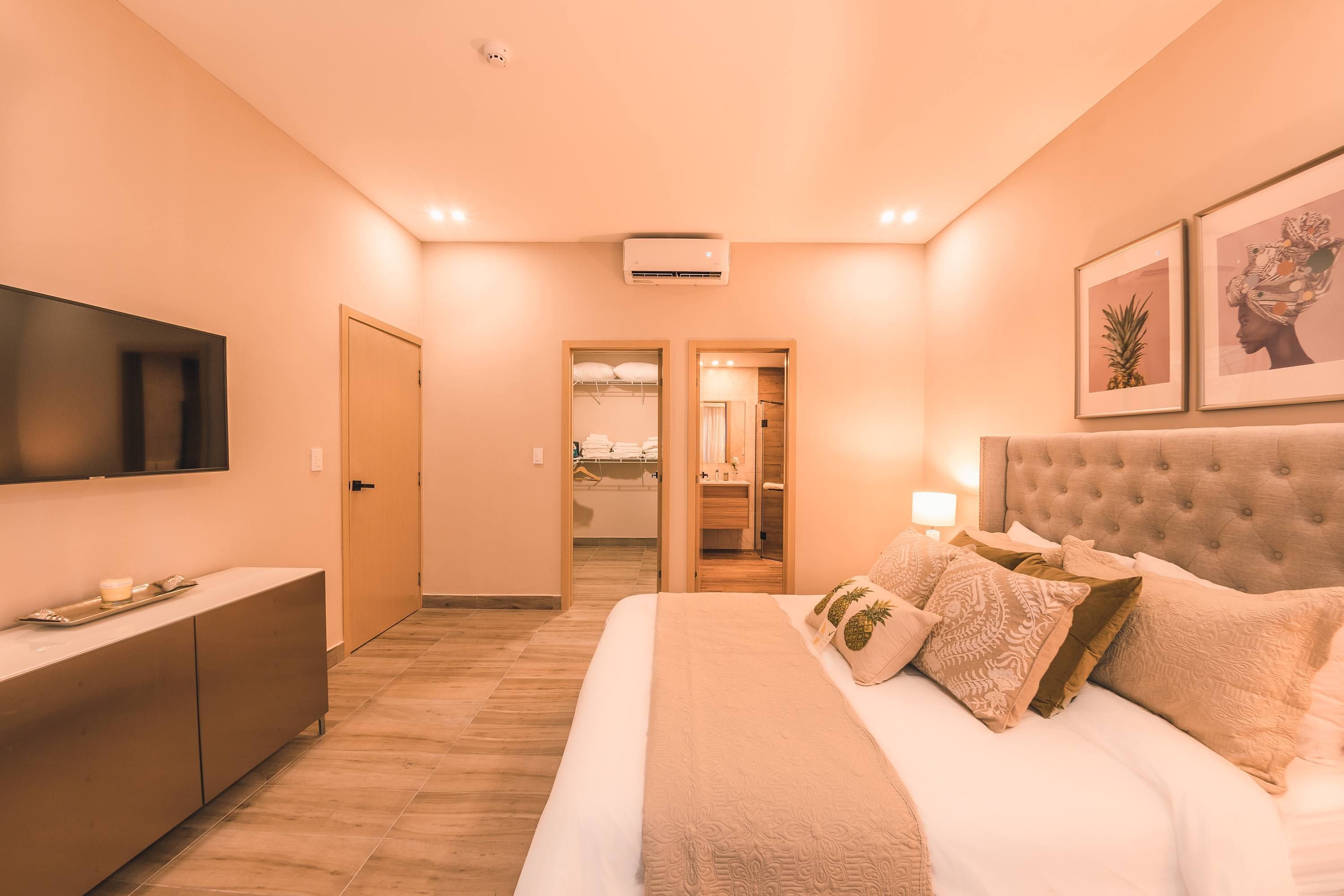 A hotel room with a bed, a TV, a wardrobe, and a bathroom visible through an open door.