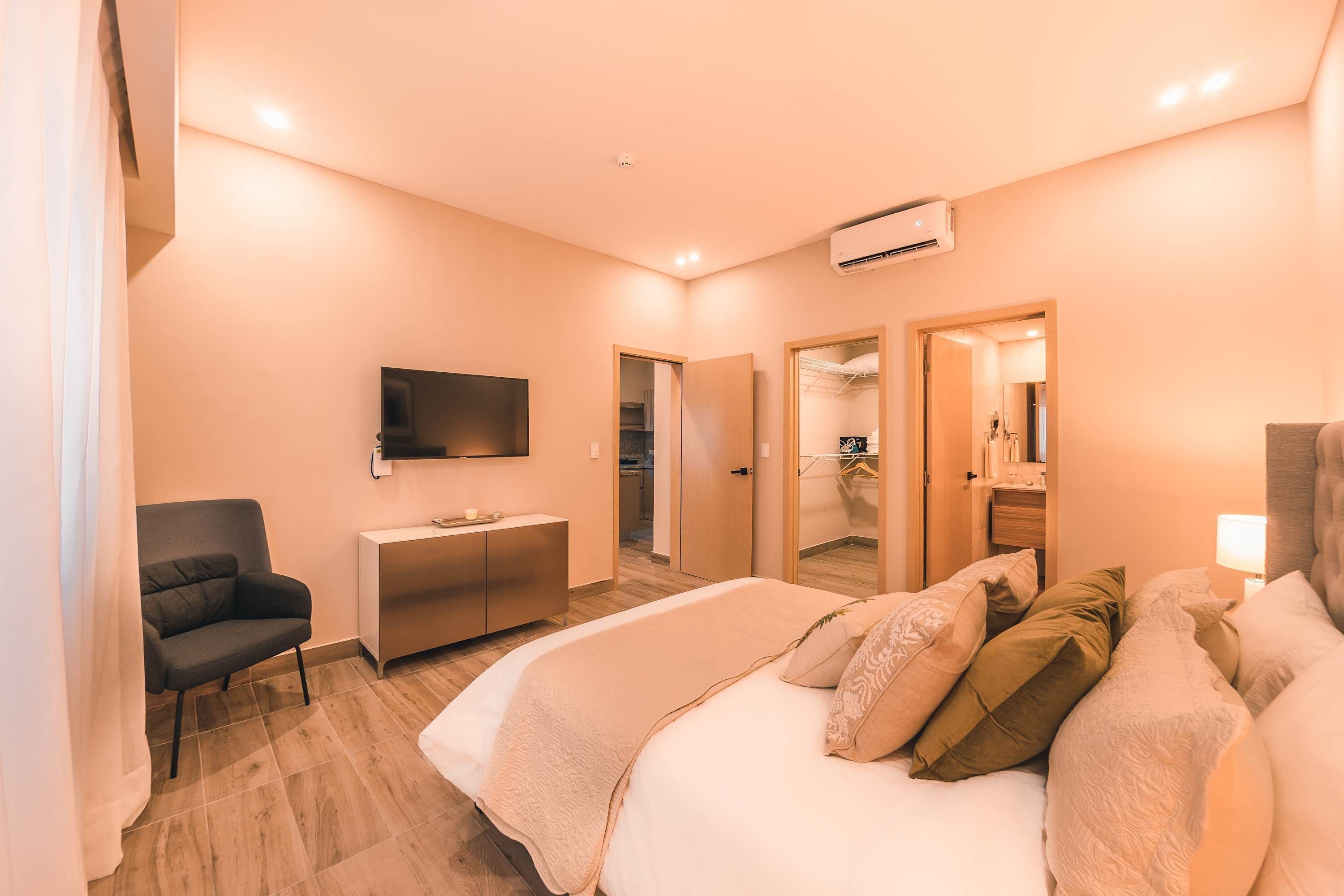 A hotel room with a bed, a desk, a chair, a TV, and a wardrobe.