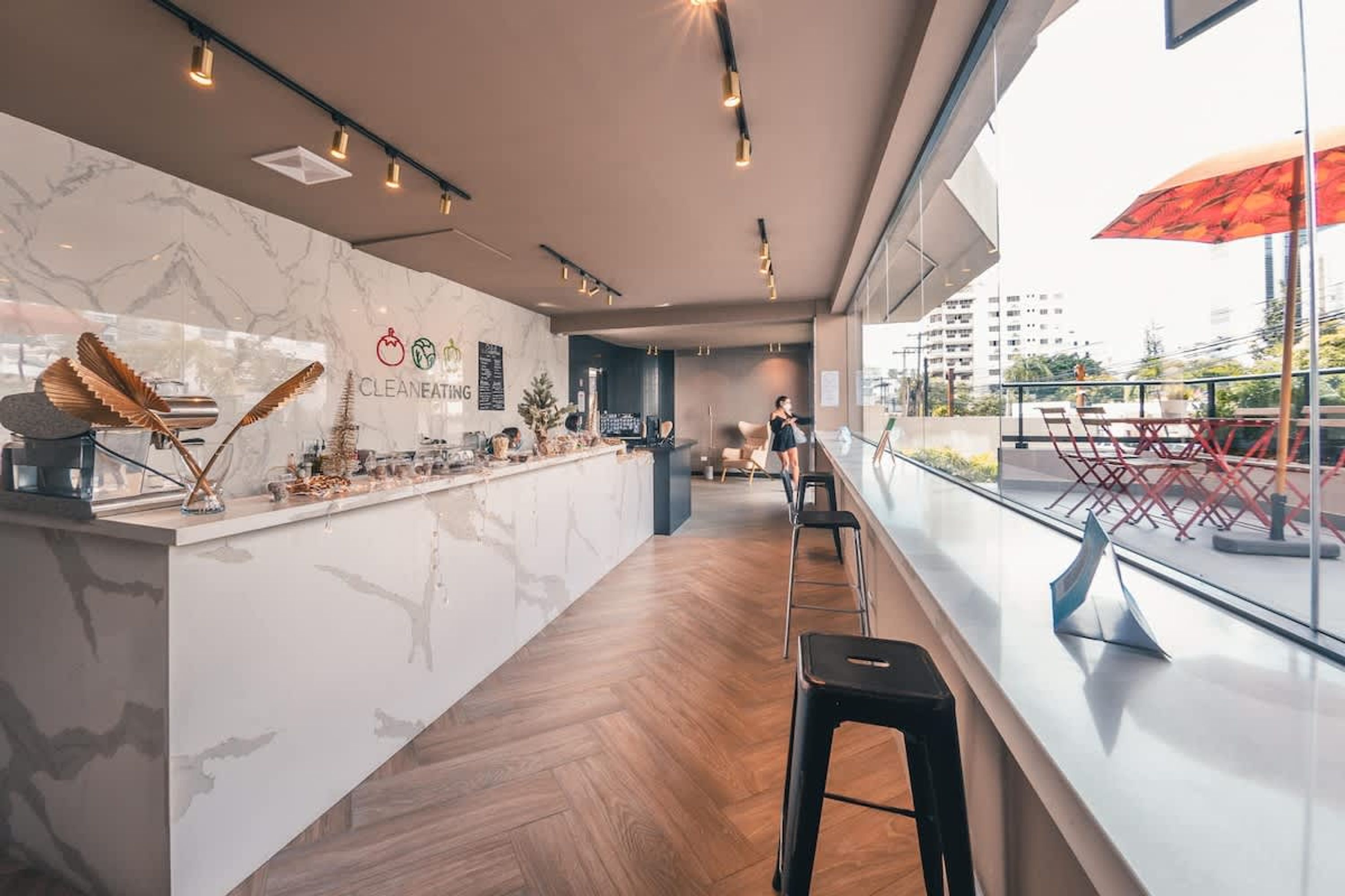 Zona de bar moderna con encimera de mármol, taburetes y vistas a la ciudad.