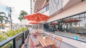 A rooftop terrace with wooden tables and red umbrellas, overlooking a cityscape. - Regatta Living 906 (Santo Domingo)