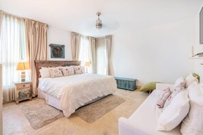 Ein Schlafzimmer mit Bett, Nachttisch, Kommode, Stuhl und Deckenventilator.