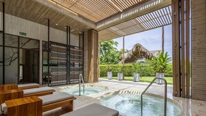 A spa area with wooden loungers, a hot tub, and a view of a thatched-roof structure. - Coastal Villa w Dock Access Pools (Cartagena)