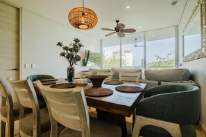 A dining area with a wooden table, woven placemats, and a vase with dried flowers. - 2-br Sea Pool View Apartment Pet-friendly (Cartagena)