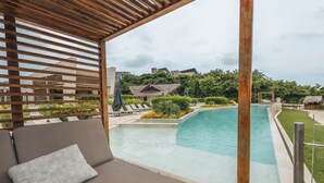 A poolside area with a wooden pergola, a cushioned seating area, and a view of a pool and surrounding greenery. - Tropical Villa w Pool Dock Access (Cartagena)
