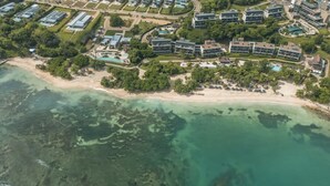 An aerial view of a coastal resort with multiple buildings, a beach, and clear turquoise waters. - Tropical Villa w Pool Dock Access (Cartagena)