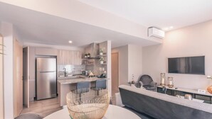 A modern kitchen with a built-in refrigerator, a dining area with a sofa and chairs, and a flat-screen TV mounted on the wall. - Flat in Regatta Ii 204 (Santo Domingo)