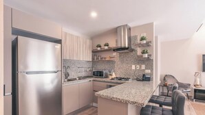 A modern kitchen with a stainless steel refrigerator, granite countertops, a gas stove, and a built-in microwave. - Flat in Regatta Ii 204 (Santo Domingo)