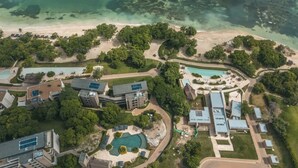 Vista aérea de un resort con varias edificaciones, una piscina y una playa.