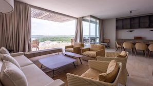 Una sala de estar moderna con un ventanal grande, un sofá, una mesita de centro y sillones de mimbre.