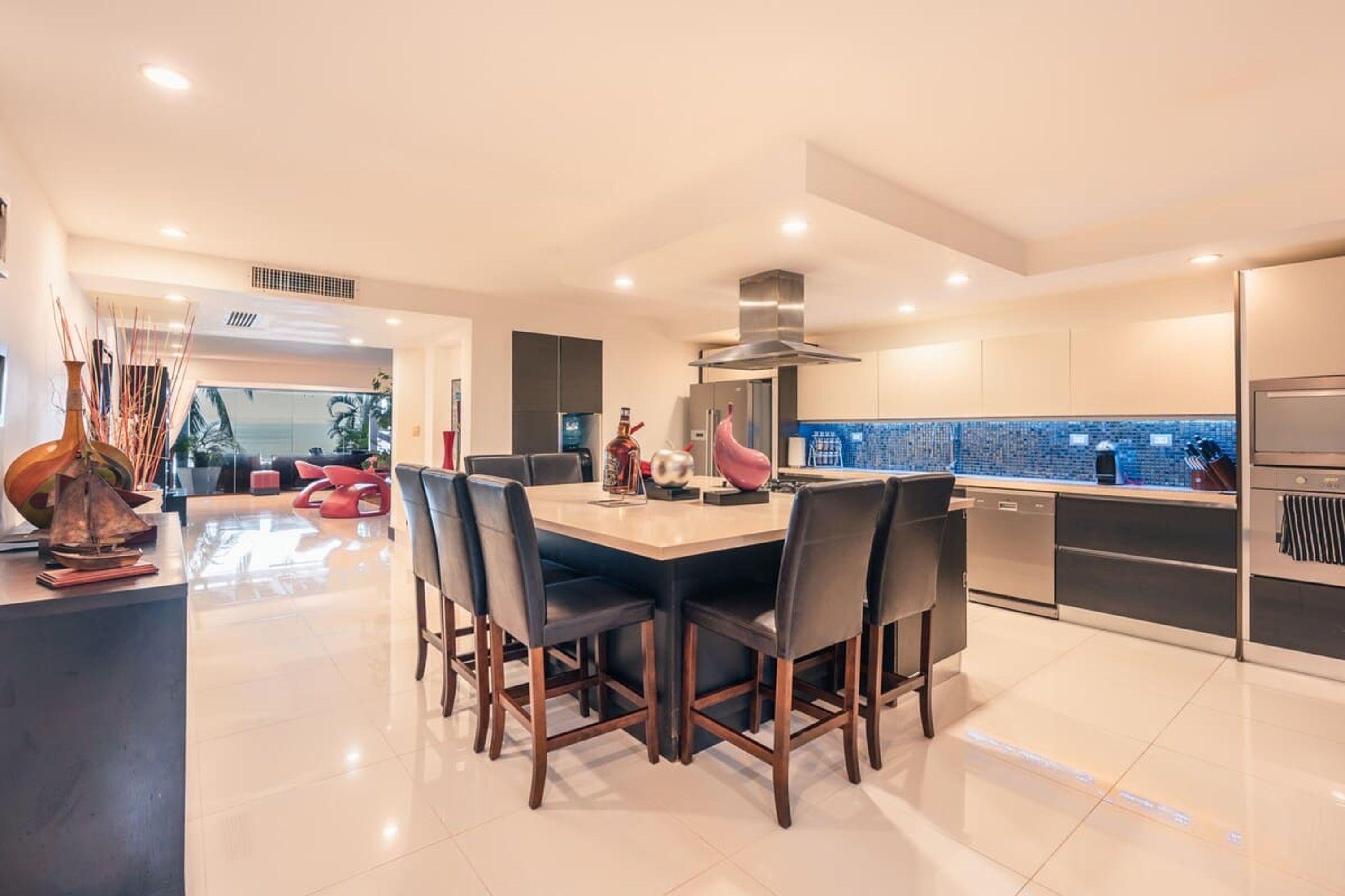 Una cuina moderna amb una illa central, electrodomèstics d'acer inoxidable i vistes cap a l'exterior.