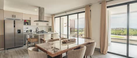 A modern kitchen with a dining area, large windows, and a view of the city.