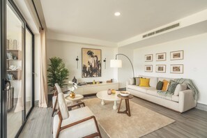 Un salon moderne avec un canapé, une table basse, des fauteuils, une plante et des œuvres d’art accrochées aux murs.