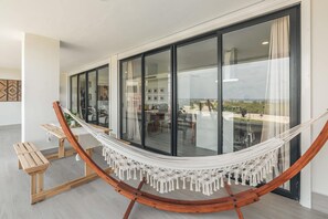 Una cadira de l'aire en una habitació moderna amb grans finestres, una banca de fusta i vista a l'exterior.
