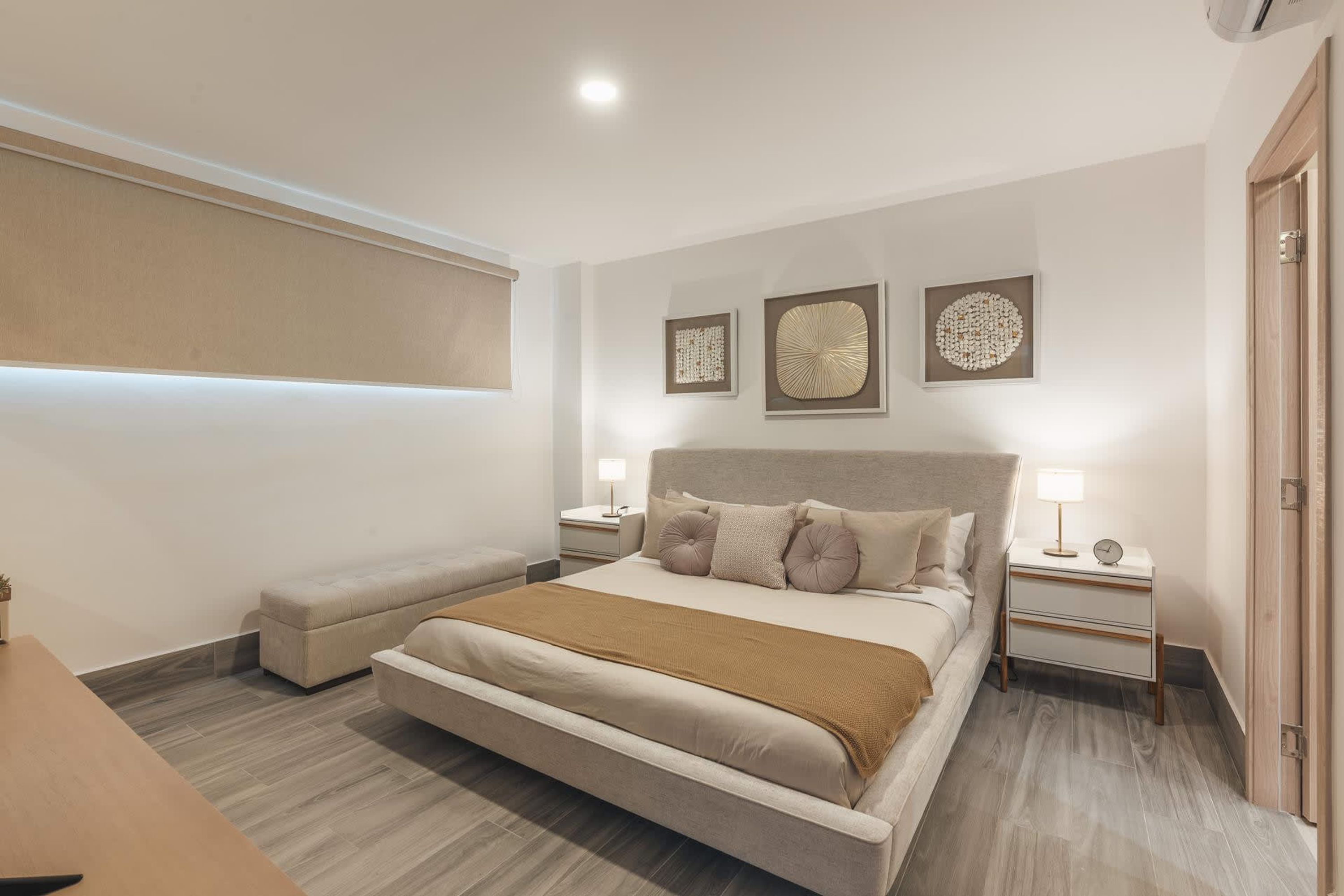 Une chambre à coucher moderne avec un grand lit, des tables de chevet et des œuvres d’art murales.